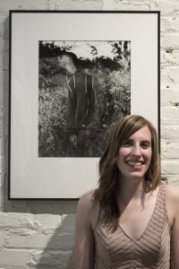 Alison posing in front of a photo at her Area 31 exhibition opening in Frederick, MD.